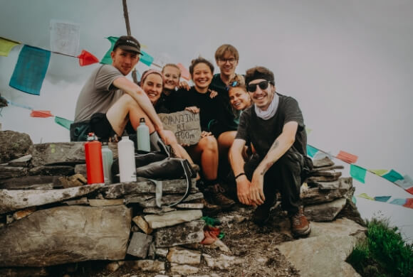 7名の男女が石垣に座りこちらを向いて笑っている